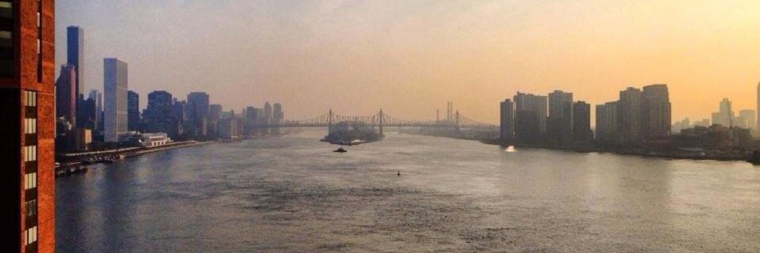 a panoramic picture of the 59th street bridge overlooking the east river at sunrise, from a downtown perspective